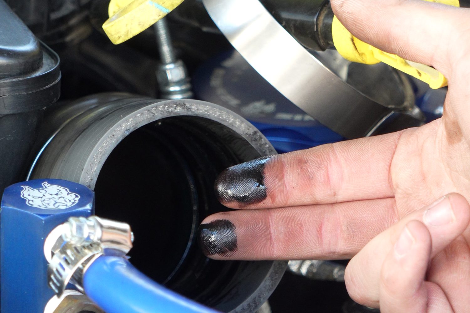 Fingertips coated in black oil after wiping the inside of a 6.7L Powerstroke intercooler pipe