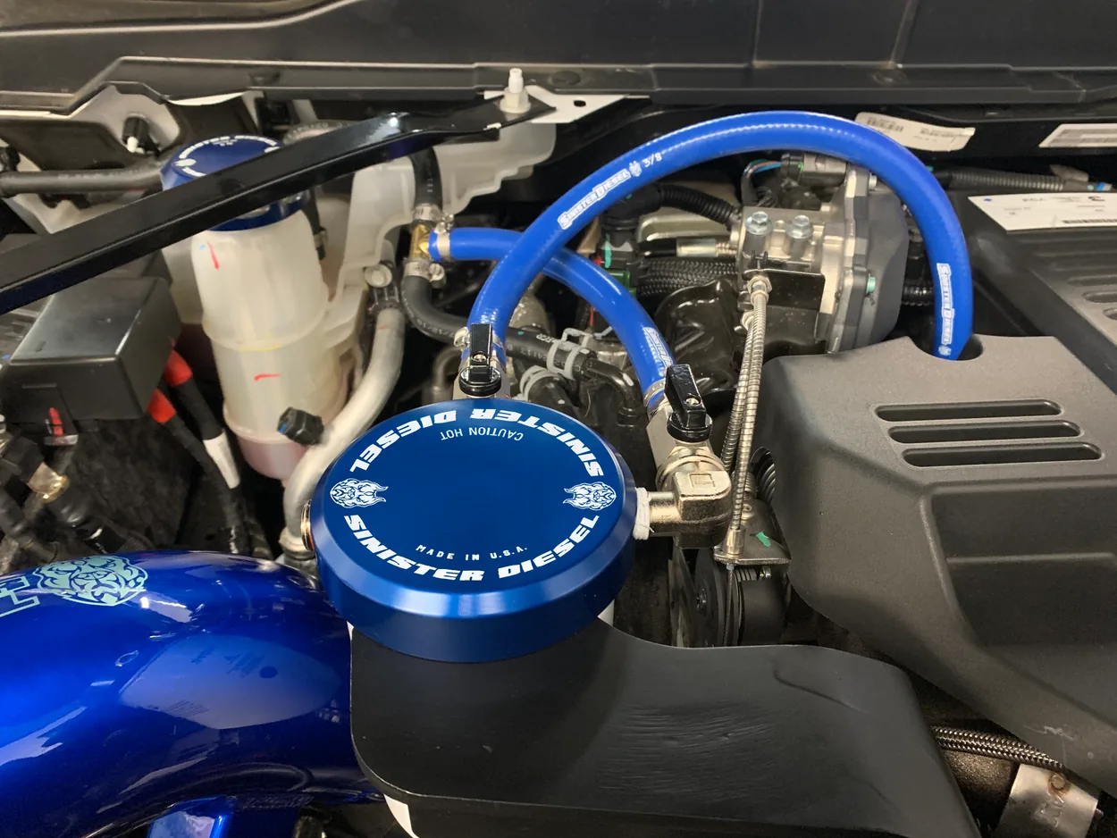 Closeup of blue Sinister Diesel coolant filtration housing and hoses installed on a Cummins truck